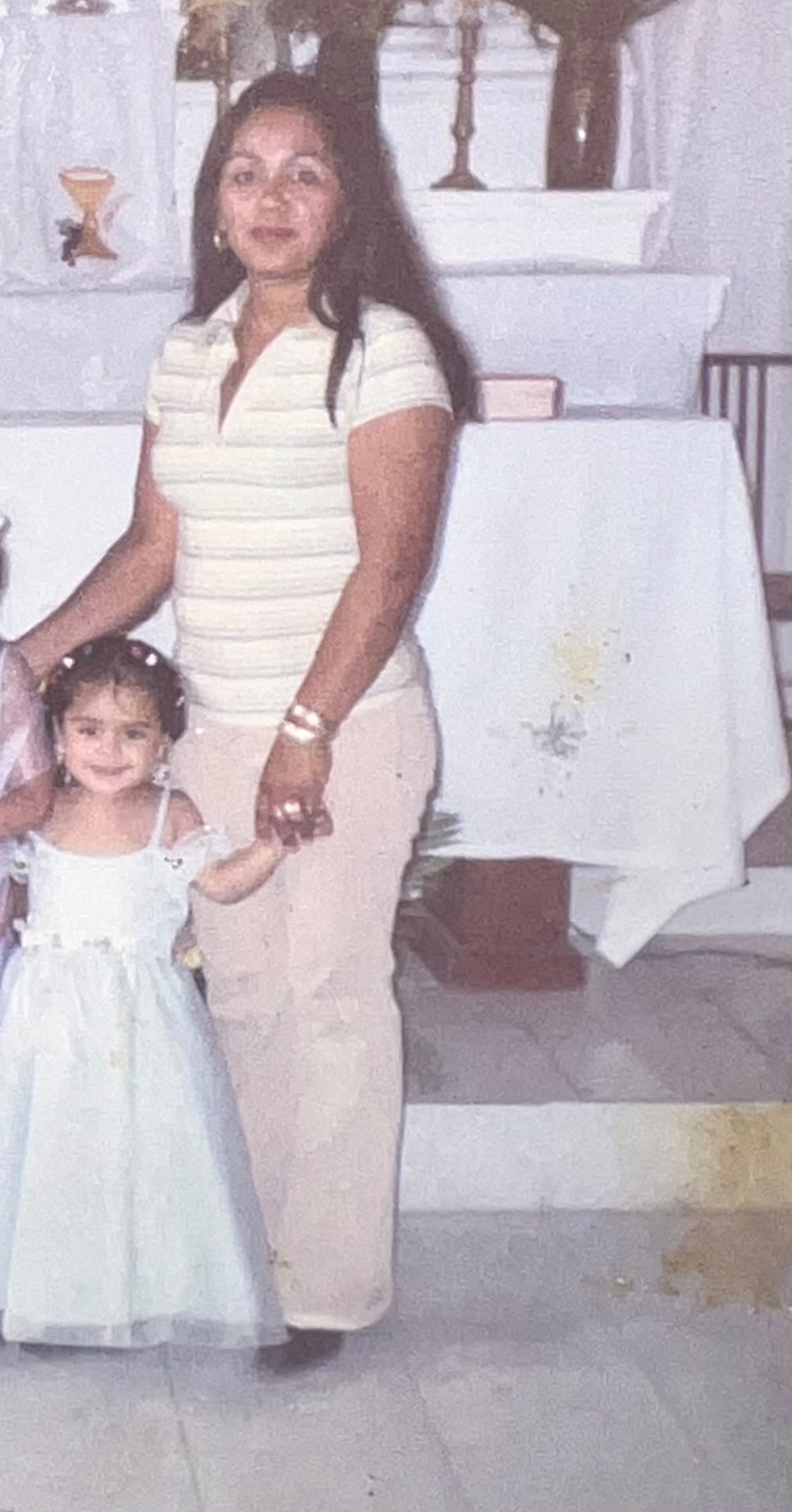 Maricela como niña, tomada de la mano de su madre